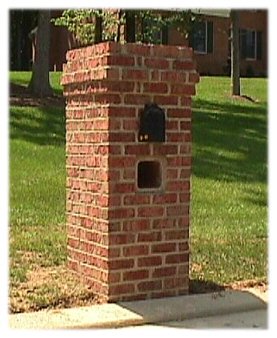 A square brick mailbox with projected brick band