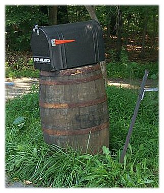 A rural metal mailbox mounted on a whiskey barrel