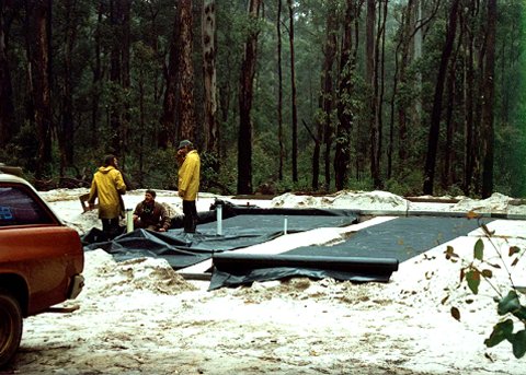 The sand pad has been sprayed for termite protection and a layer of plastic is being spread out to act as a vapor barrier.