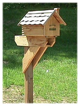 A cedar house style mailbox with shingled roof