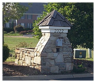 A stone mail box with a trash bin container.